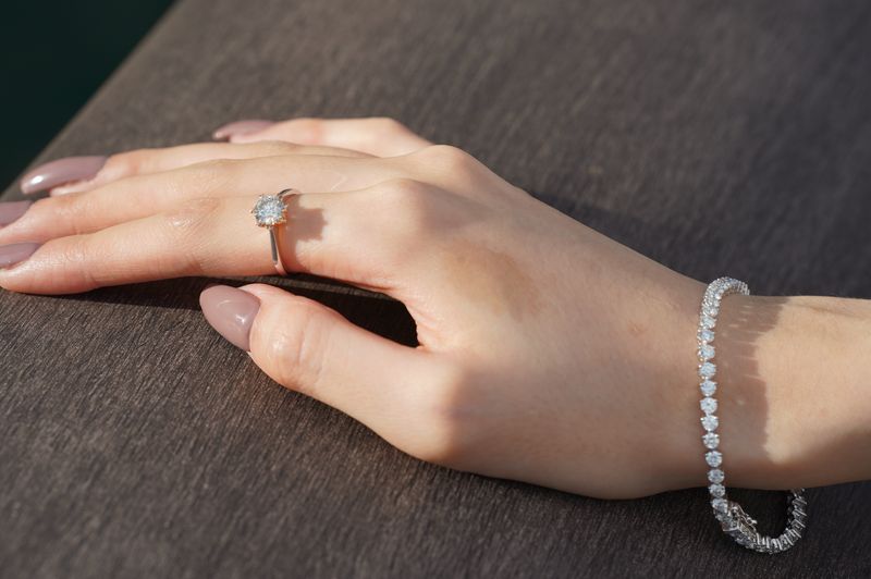 Lifestyle image of a diamond ring and bracelet displayed on a neutral background