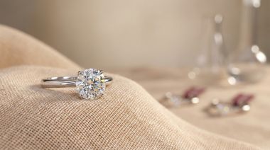 Natural diamond engagement ring in sharp focus on a soft beige fabric background, symbolising timeless value and authenticity.